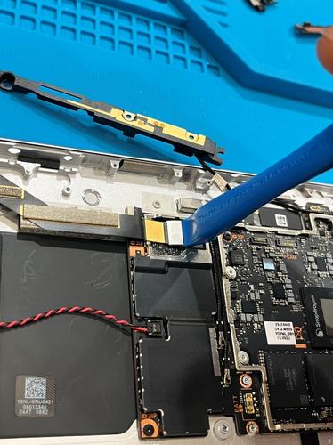 Tool positioned to disconnect the rear camera FPC connector.